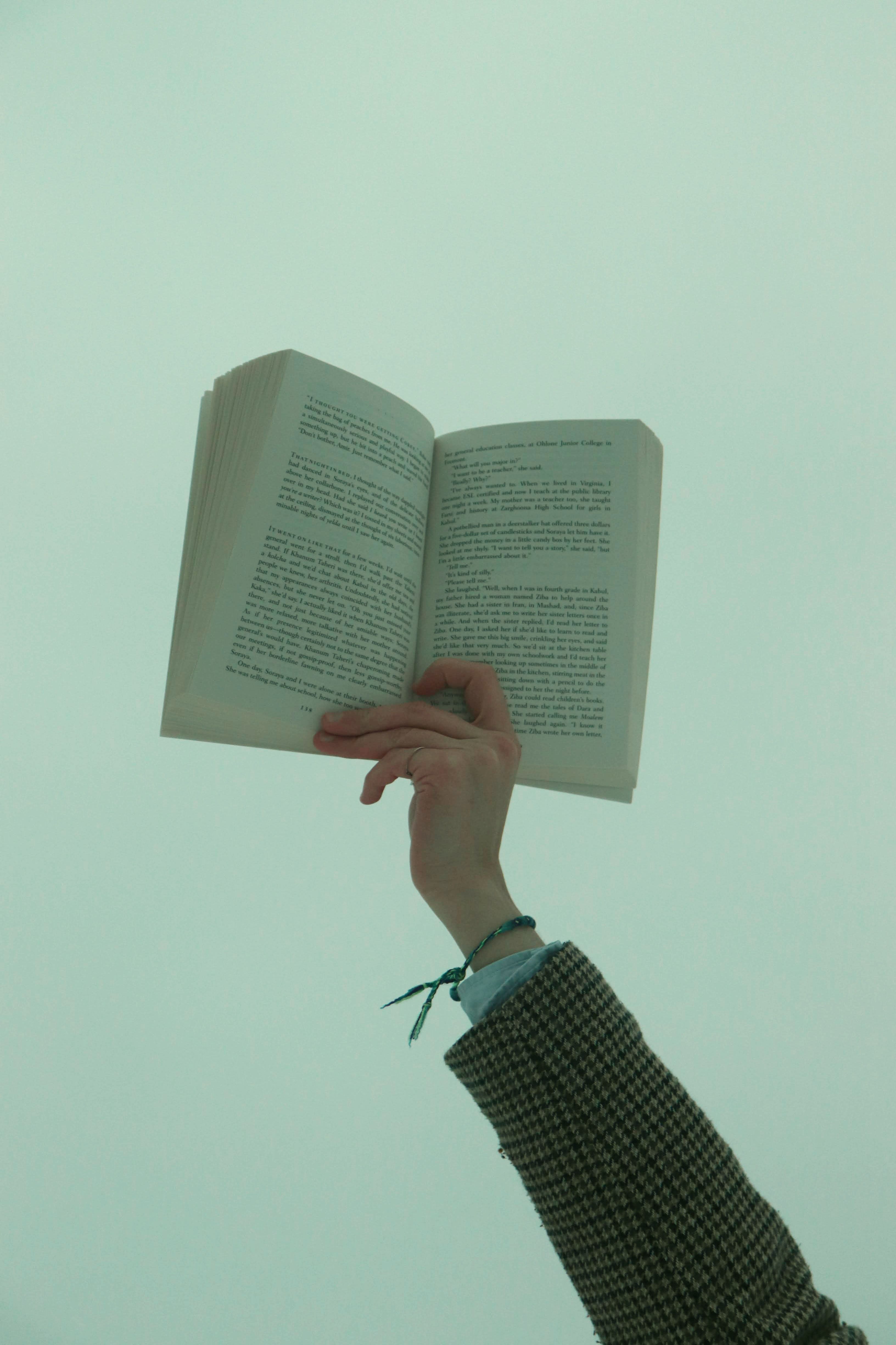 Raised Arm Holding Open Book · Free Stock Photo