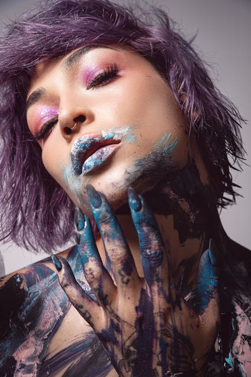Artistic Studio Shot of a Woman with Painted Face and Purple Hair