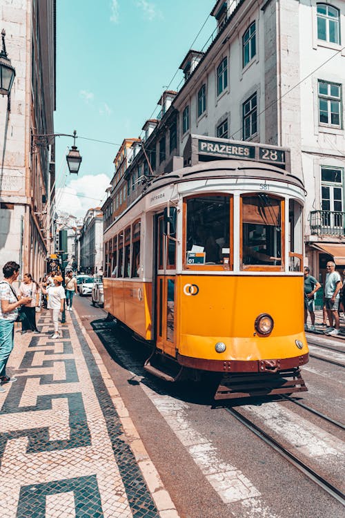 A yellow tram is traveling down a street