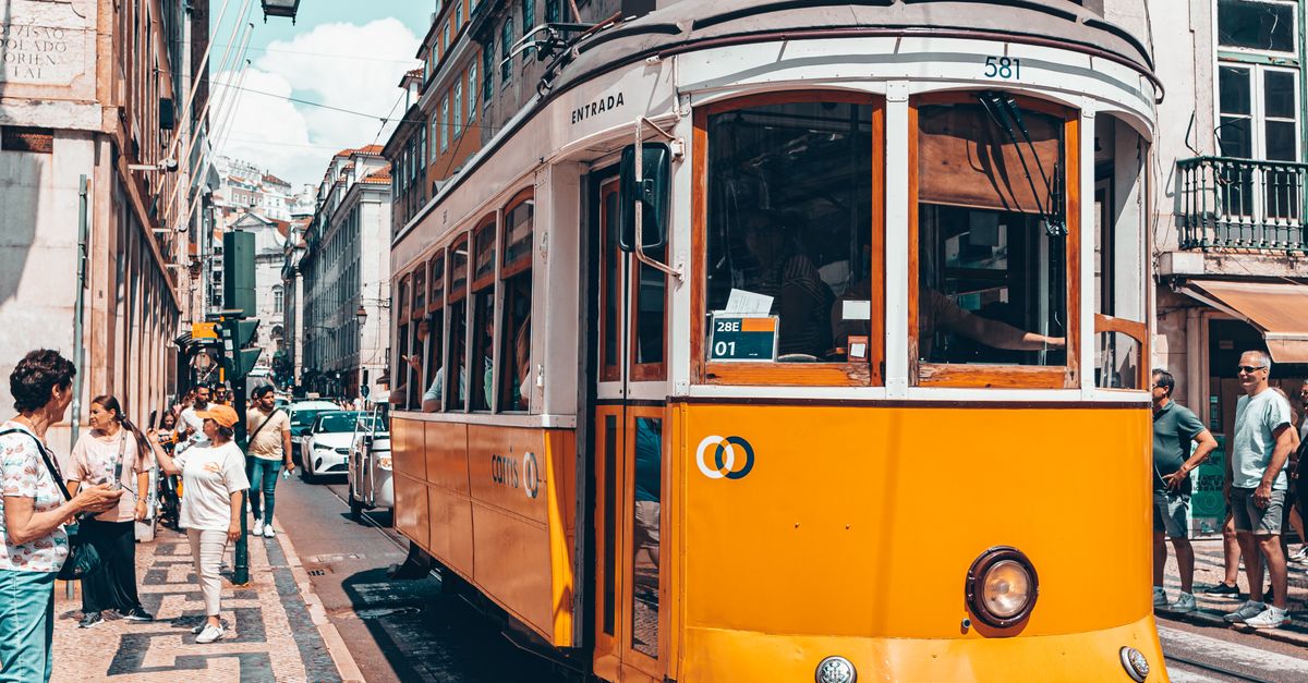 Vibrant yellow tram number 28 in Lisbon, Portugal, surrounded by urban life and classic architecture.