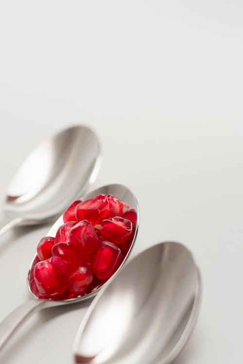 Free Pomegranate Seed on Spoon Between Empty Spoons Stock Photo