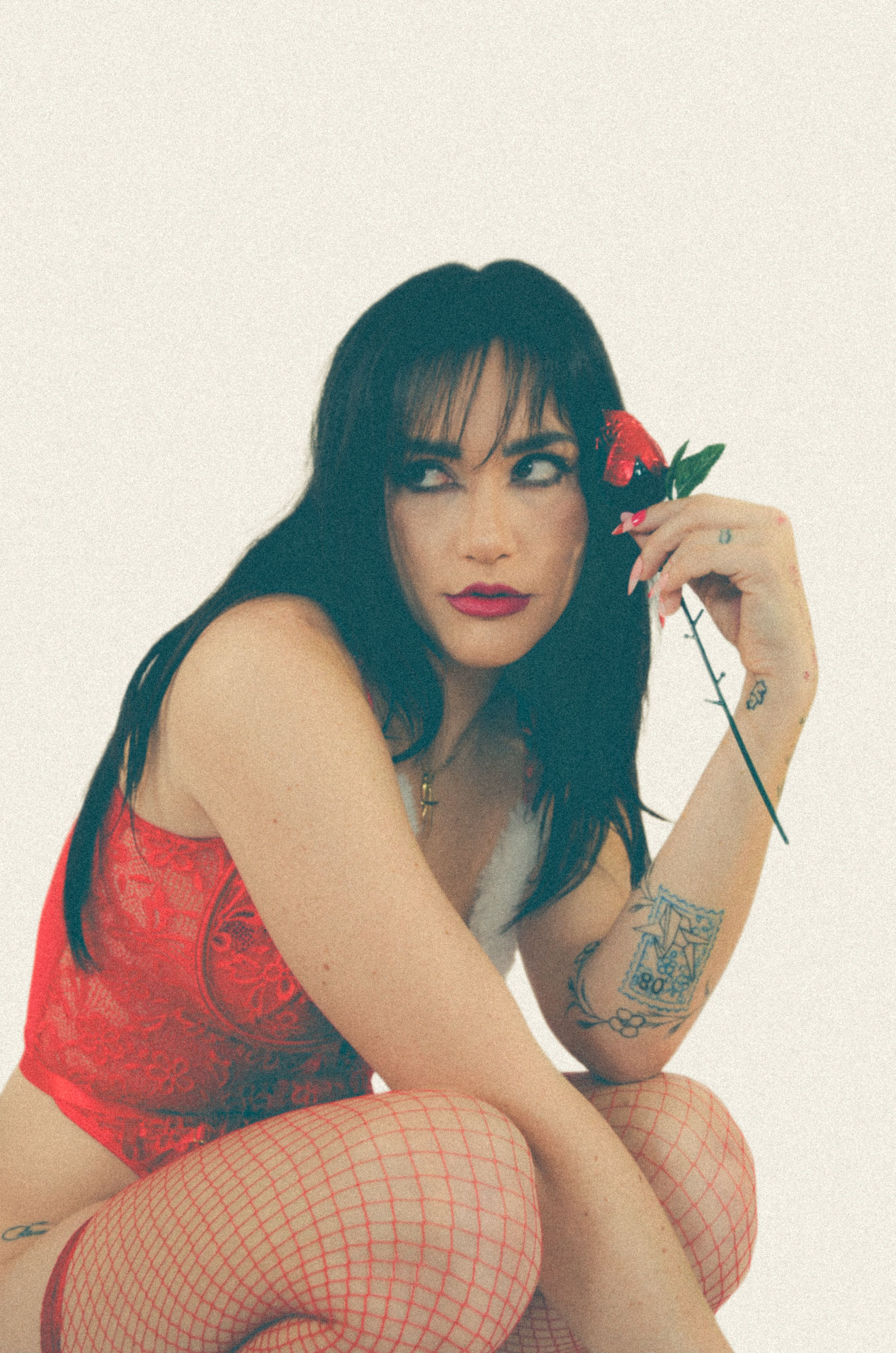 Portrait of a woman in red lingerie holding a rose, exuding elegance and allure.