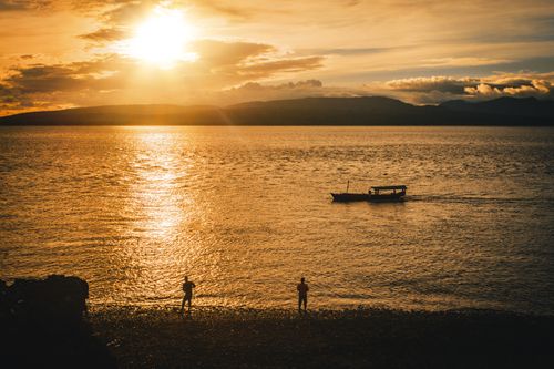 Free Peaceful sunset with silhouettes and boat on the Jawa Timur shore. Stock Photo