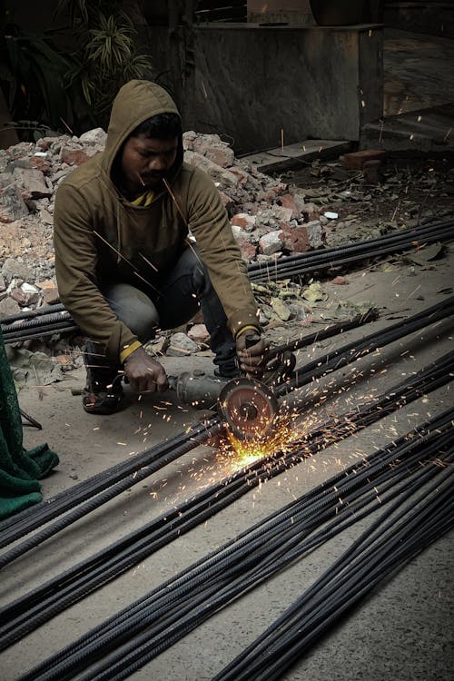 Man in Hoodie Grinding Steel Bars