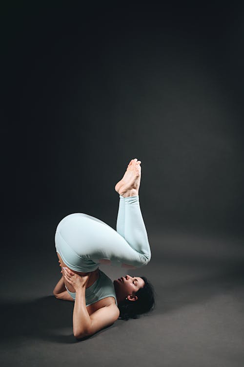 Brunette Woman Performing Gymnastics in Dark Studio