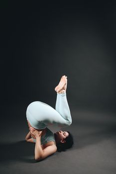 Woman performing challenging yoga pose showing strength and flexibility in an indoor studio setup.
