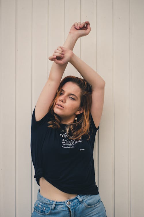 Woman Raising Her Both Arms While Standing Near Wall