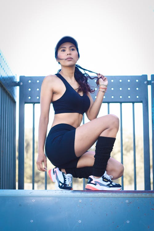 Brunette Fit Woman in Black Top Crouching by Railing