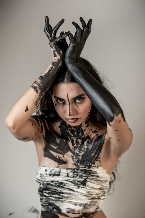 Free Striking studio portrait of a woman with black body paint and expressive pose. Stock Photo