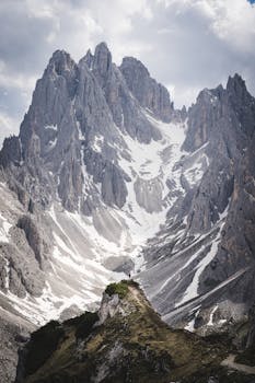 Stunning view of the snowcapped Cadini di Misurina peaks in the Dolomites, Italy under a cloudy sky.
