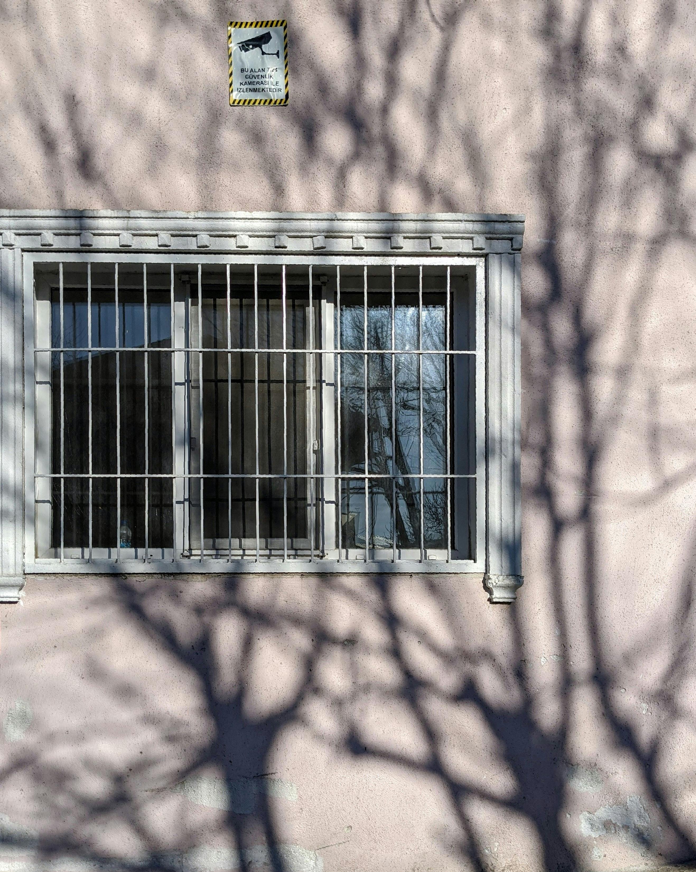 Exterior wall with barred window and tree shadows in Istanbul, Türkiye.