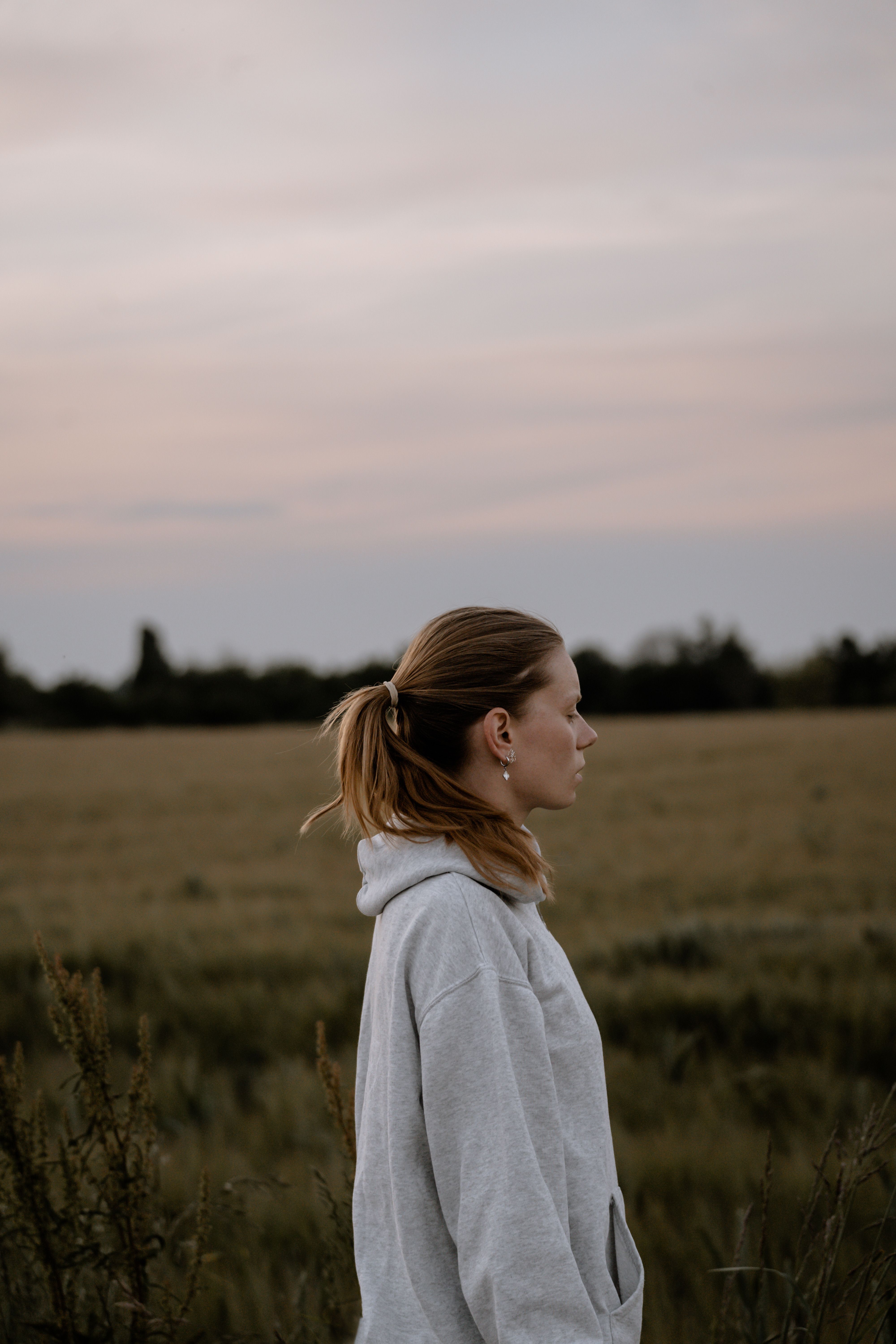 Woman in Hoodie Standing on Field · Free Stock Photo