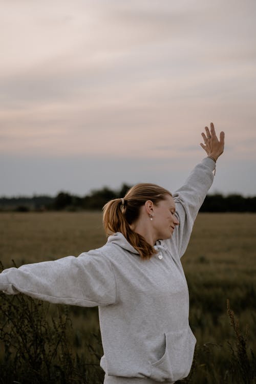 A woman in a field with her arms outstretched