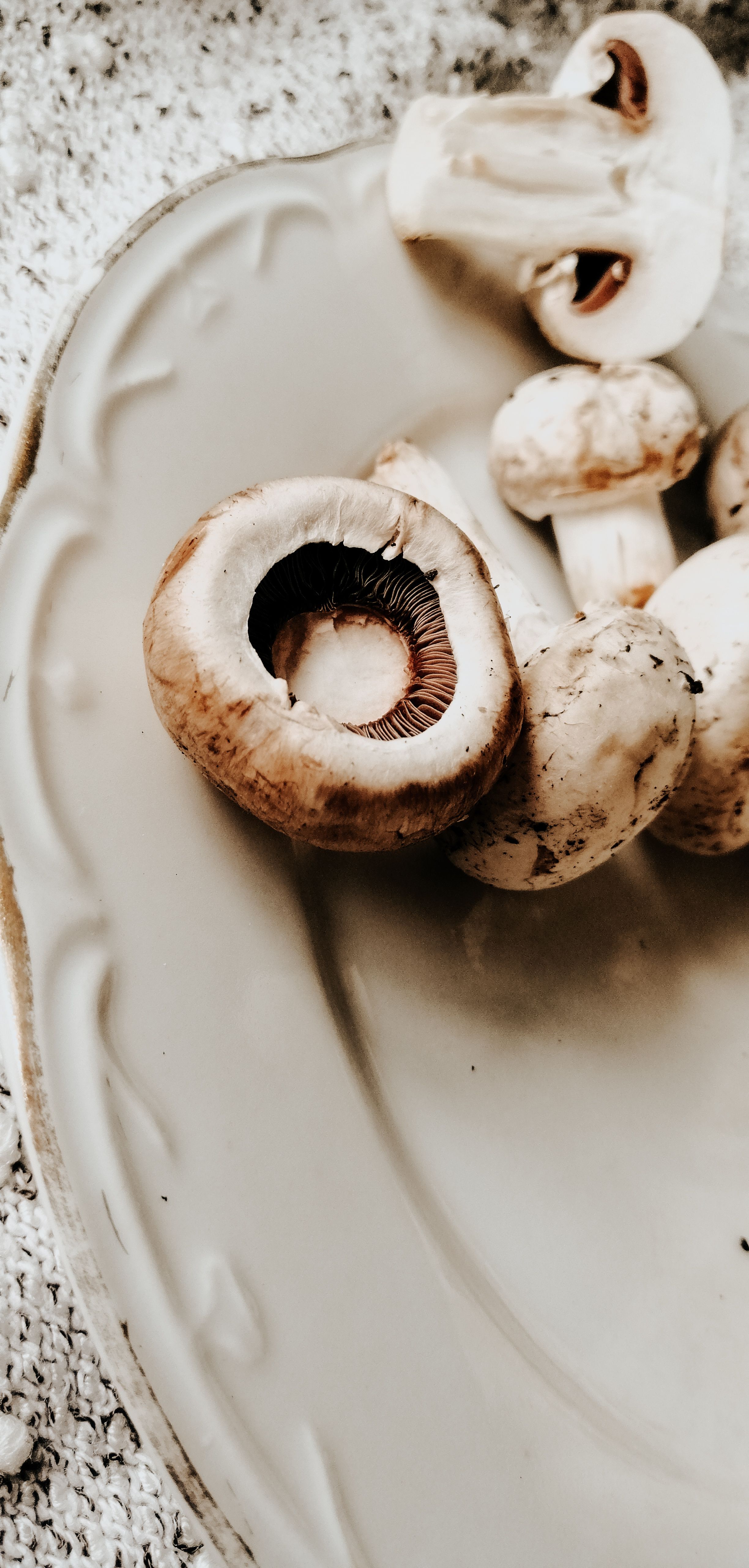 Fotomural Una vista en primer plano de champiñones crudos en un plato decorativo de cerámica, resaltando su textura natural y tonos terrosos.