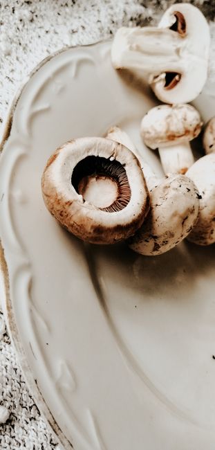 Fotomural Una vista en primer plano de champiñones crudos en un plato decorativo de cerámica, resaltando su textura natural y tonos terrosos.