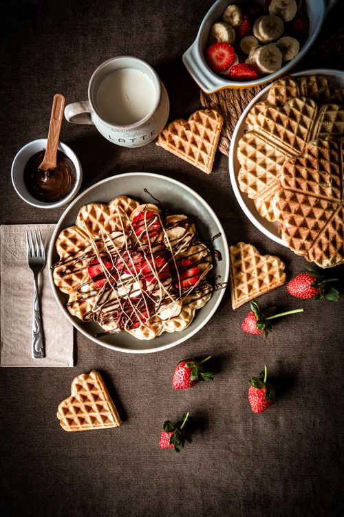 Free Delicious heart-shaped waffles topped with chocolate and strawberries, perfect breakfast treat. Stock Photo