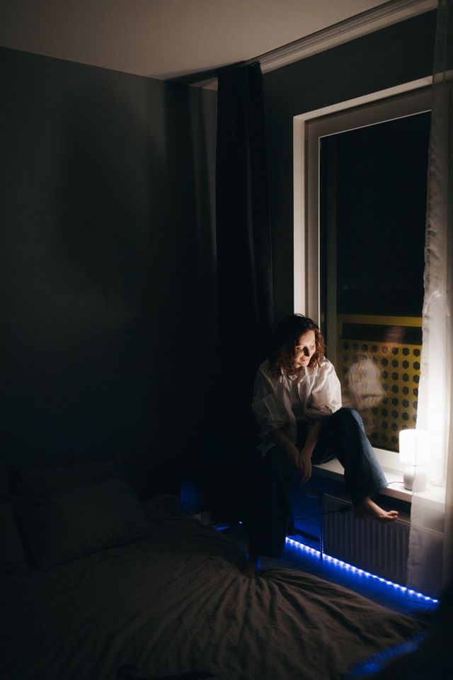Dim bedroom at night lit by a blue LED strip, photo by Margarita on Pexels