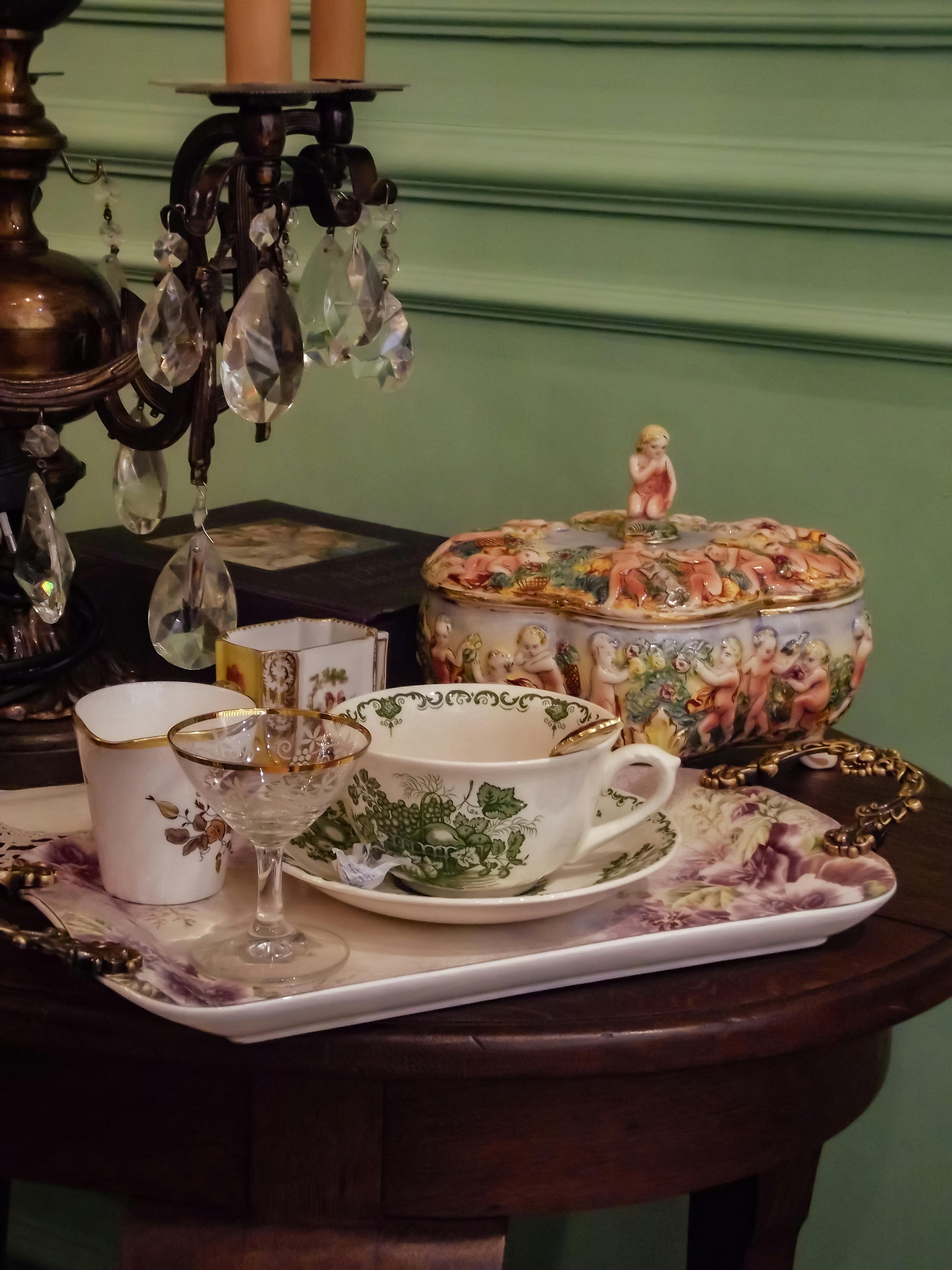 A close-up of a vintage tea set with ornate designs on an antique table, evoking classic elegance.