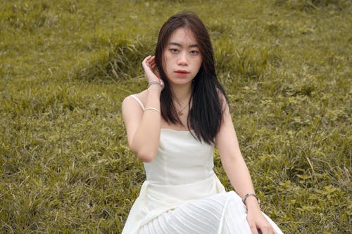 A woman sitting in a field wearing white