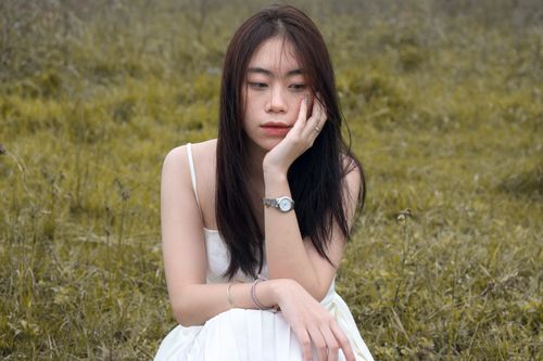 Free Thoughtful moment of a woman sitting in a meadow wearing a white dress. Stock Photo