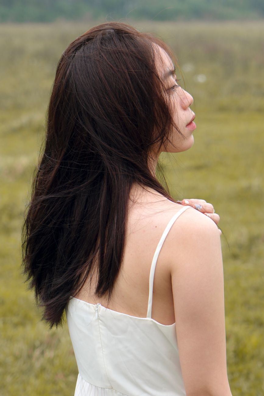 A serene portrait of a woman with flowing hair standing in a field, showcasing elegance and tranquility.