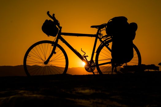 Silhouette of a bicycle against a vibrant sunset, evoking adventure and freedom.