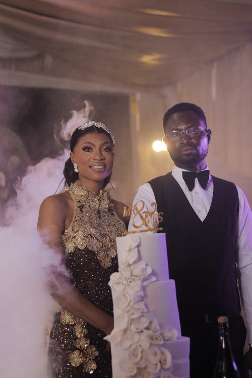 A man and woman standing next to a cake