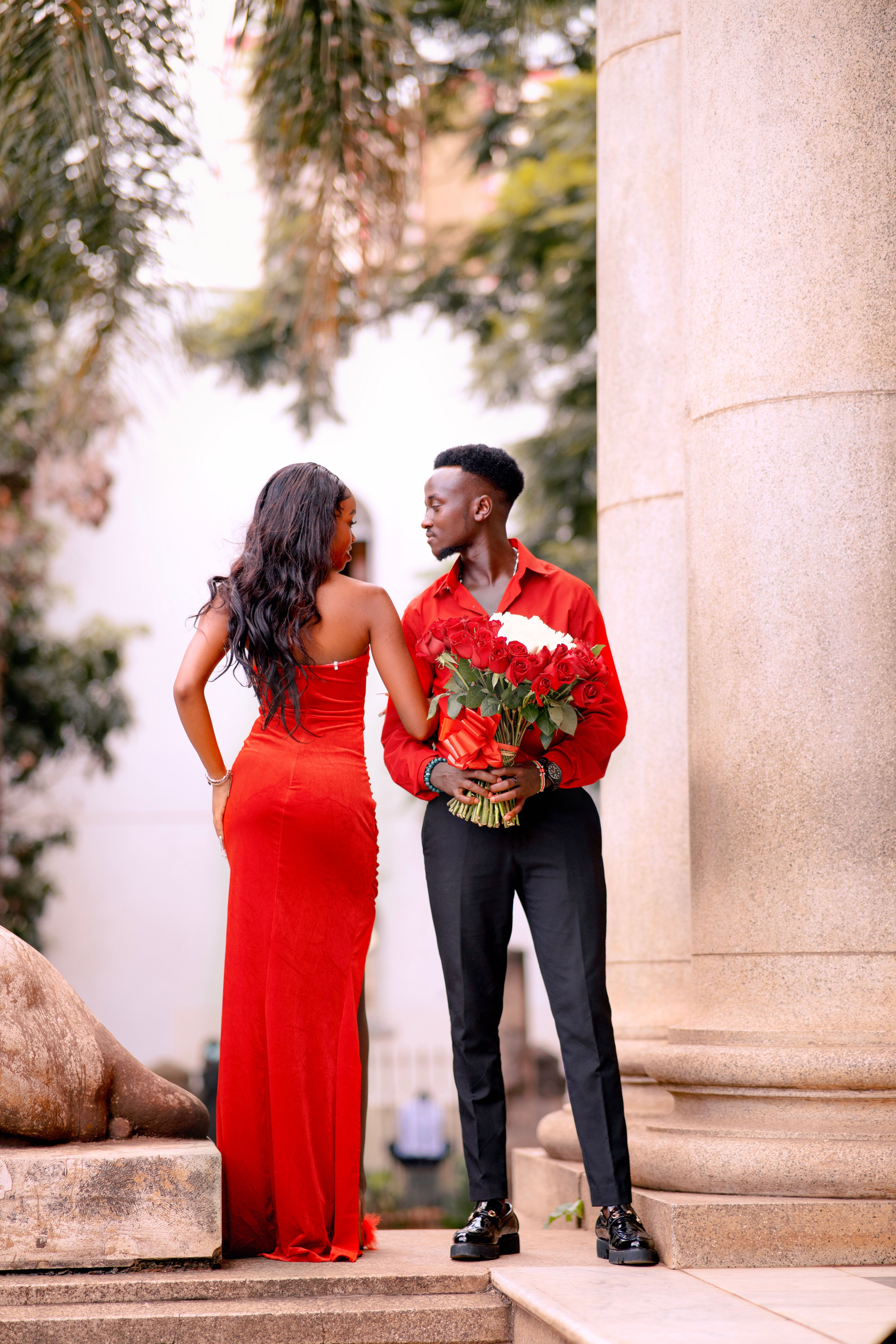 A stylish couple stands together outdoors with a bouquet, highlighting elegance and romance.