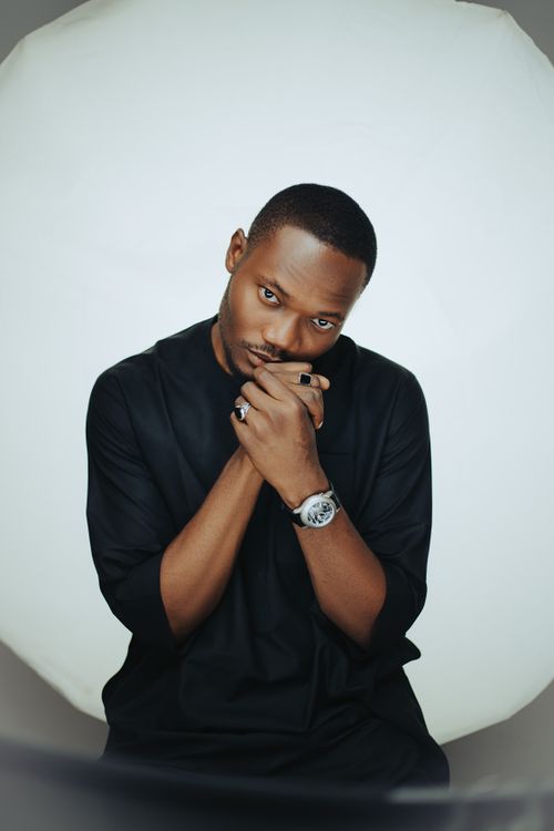 Free Elegant portrait of an African American man in a black outfit, posing with a wristwatch in studio lighting. Stock Photo