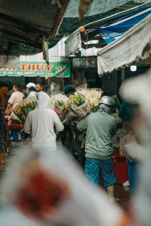 People walking through a market with flowers