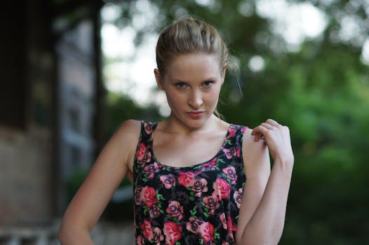 A young woman posing outdoors in a floral top, exuding confidence and style.