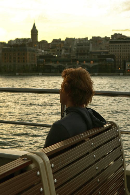 A person sitting on a bench looking at a body of water