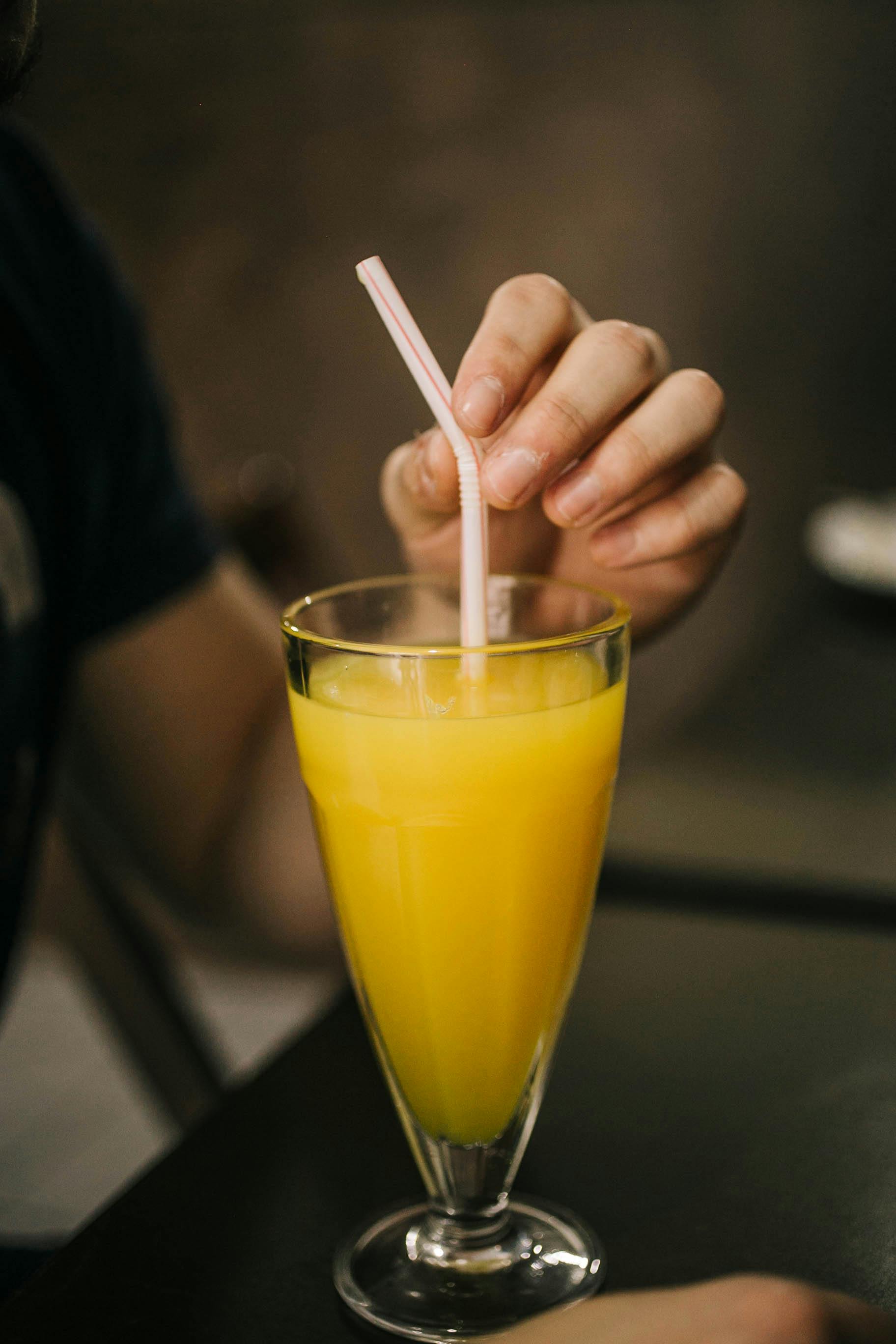 man hand holding straw in juice glass