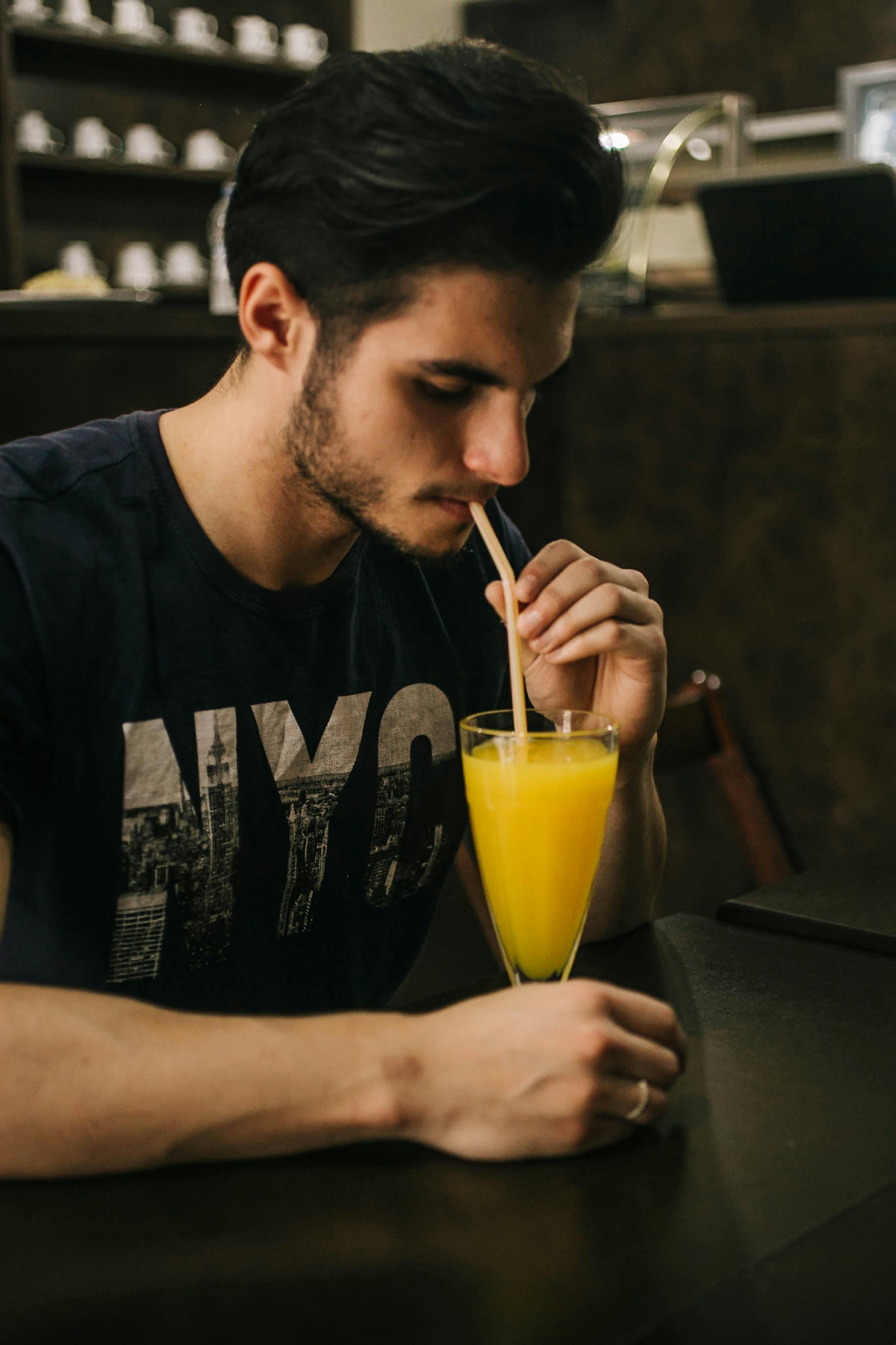 man sitting and drinking juice with straw