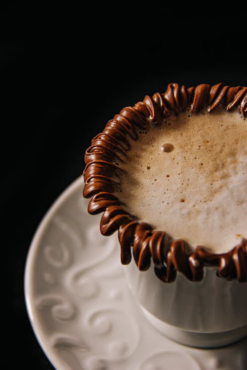 A cup of coffee with chocolate swirls on top