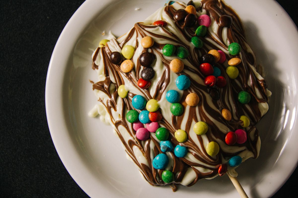 A delicious dessert with colorful candies and chocolate swirls on a plate.