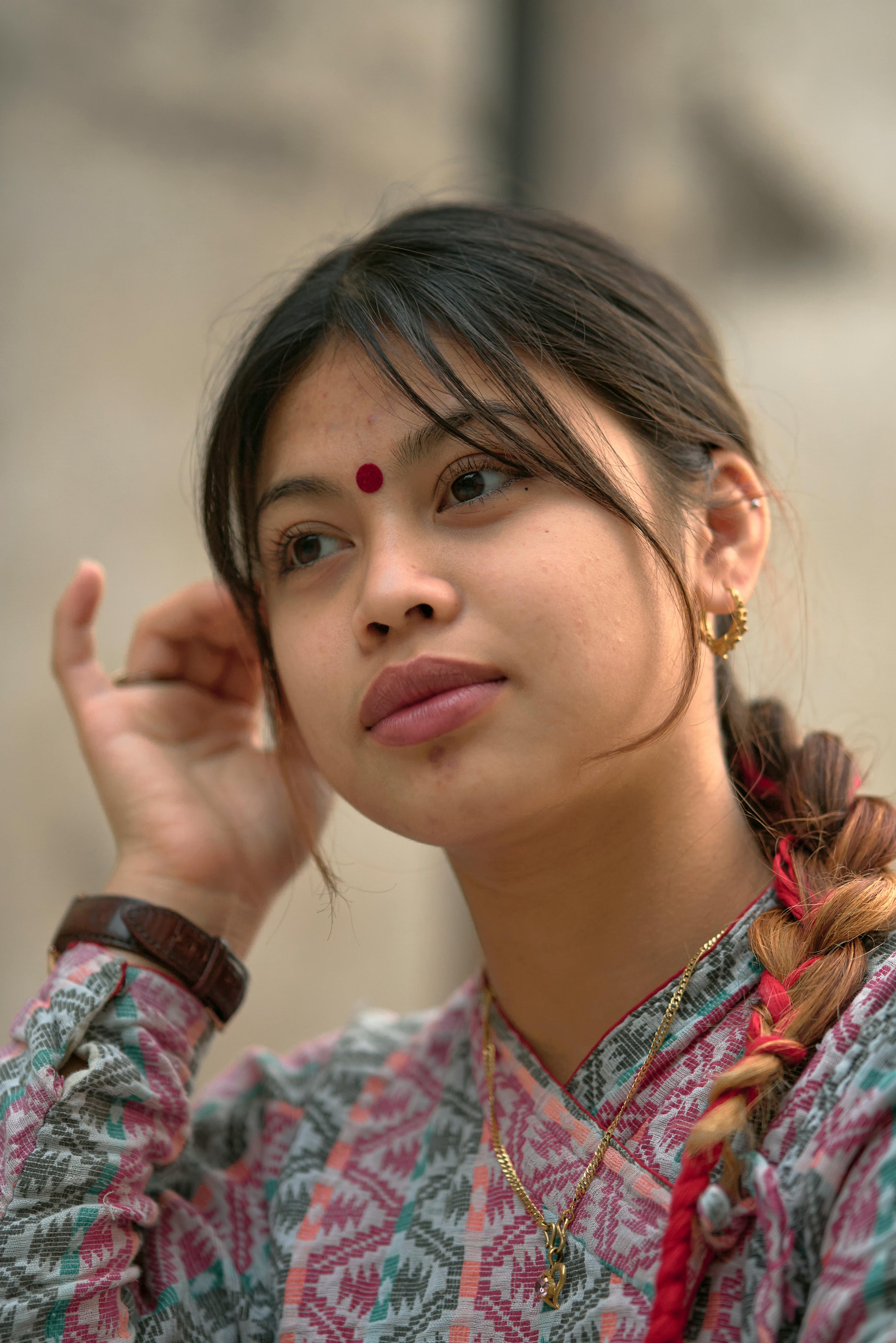A captivating portrait of a South Asian woman adjusting her hair, wearing traditional attire and jewelry.