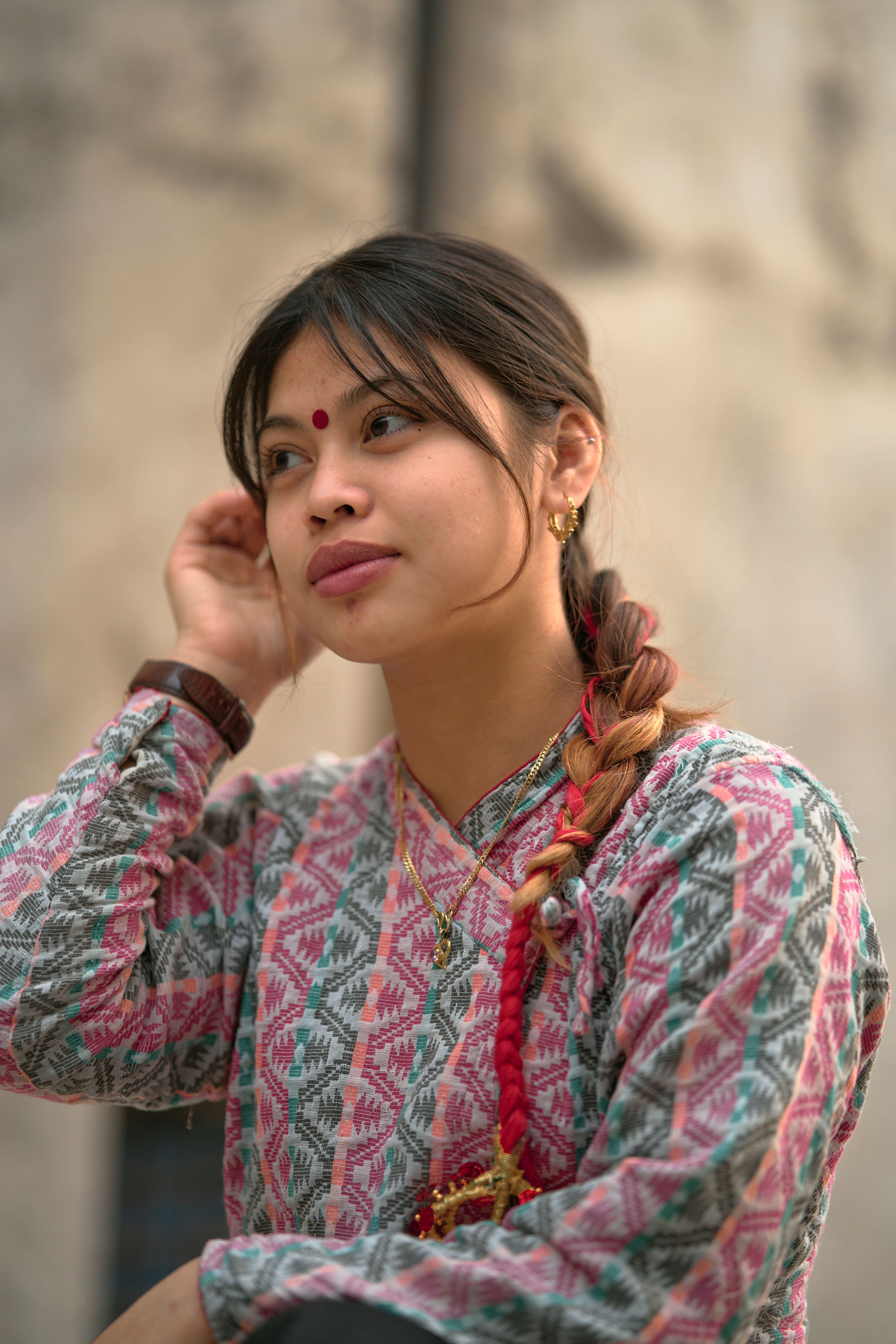 Woman in traditional South Asian clothing with braided hair, captured in a warm portrait setting.
