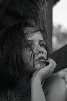 一幅黑白肖像画中，一位头发飘逸的人陷入沉思