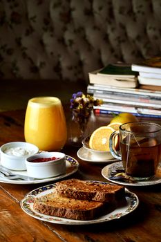 A cozy breakfast spread featuring toast, tea, orange juice, and various side dishes on a wooden table.