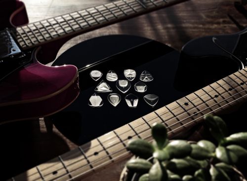 Free Close-up of electric guitars and picks arranged on a reflective surface, accented by natural light. Stock Photo