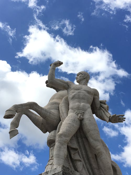 A statue of a man on a horse with clouds in the sky