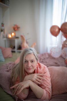 A serene portrait of a woman relaxing on a bed in a cozy room with festive balloons.