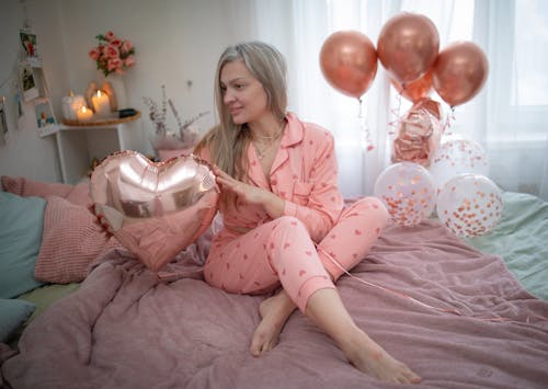 Woman in Pajama and with Balloons on Bed