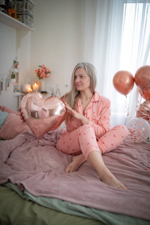 Free Woman Sitting with Balloons on Bed Stock Photo