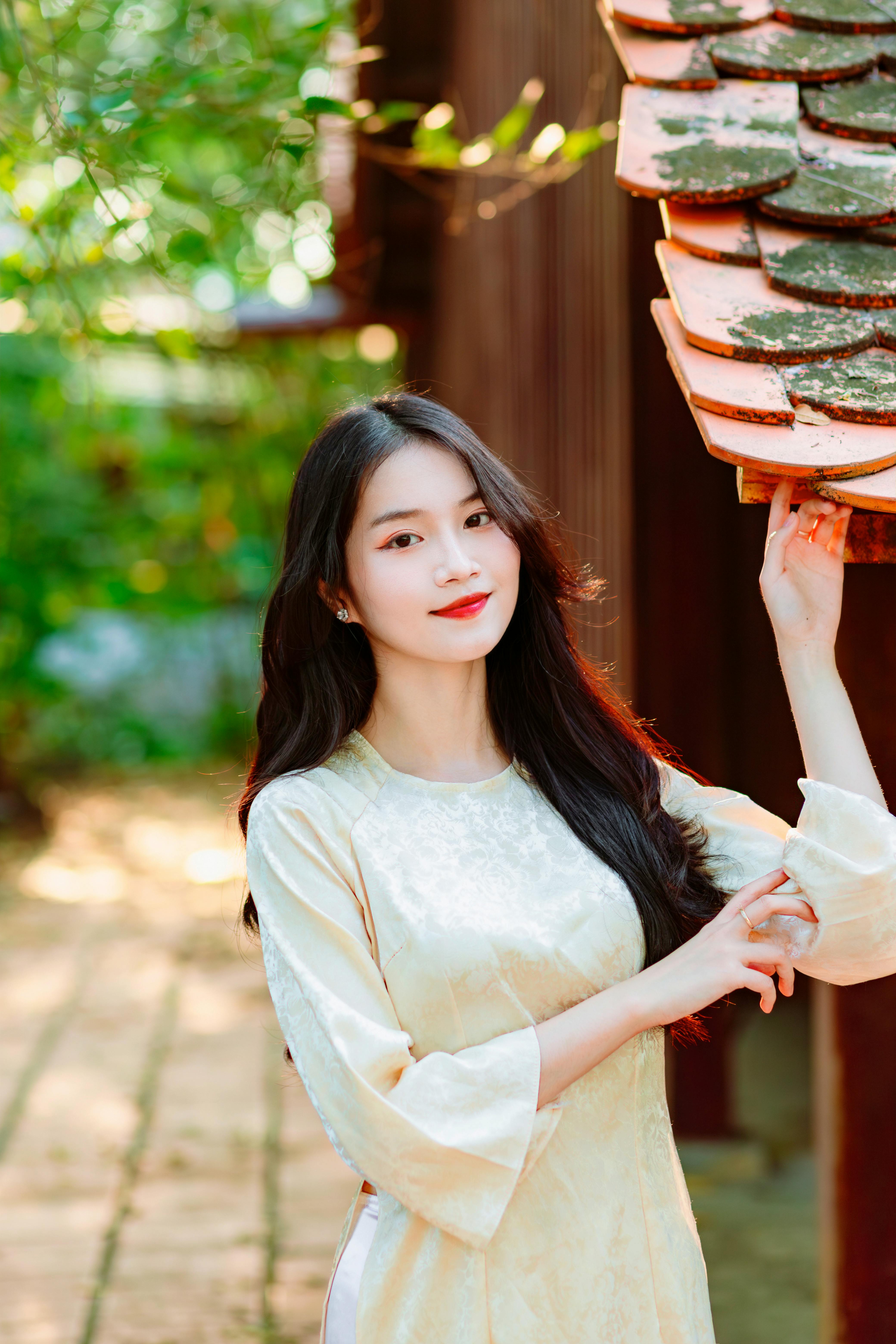 Young woman in a silk dress enjoying a sunny day outdoors, capturing a serene and fashionable moment.