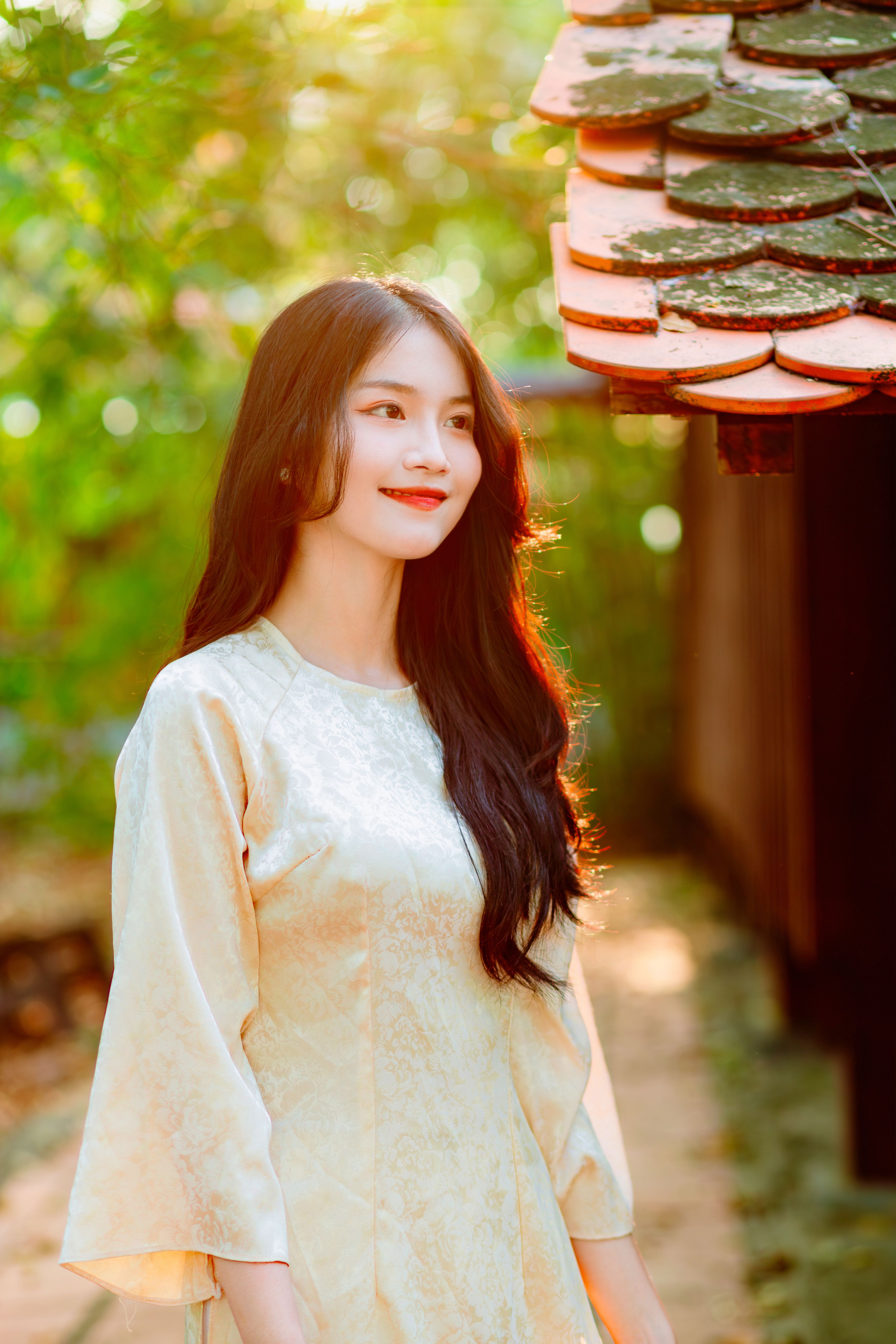 Portrait of a smiling woman in a cream dress, enjoying nature's beauty during golden hour.