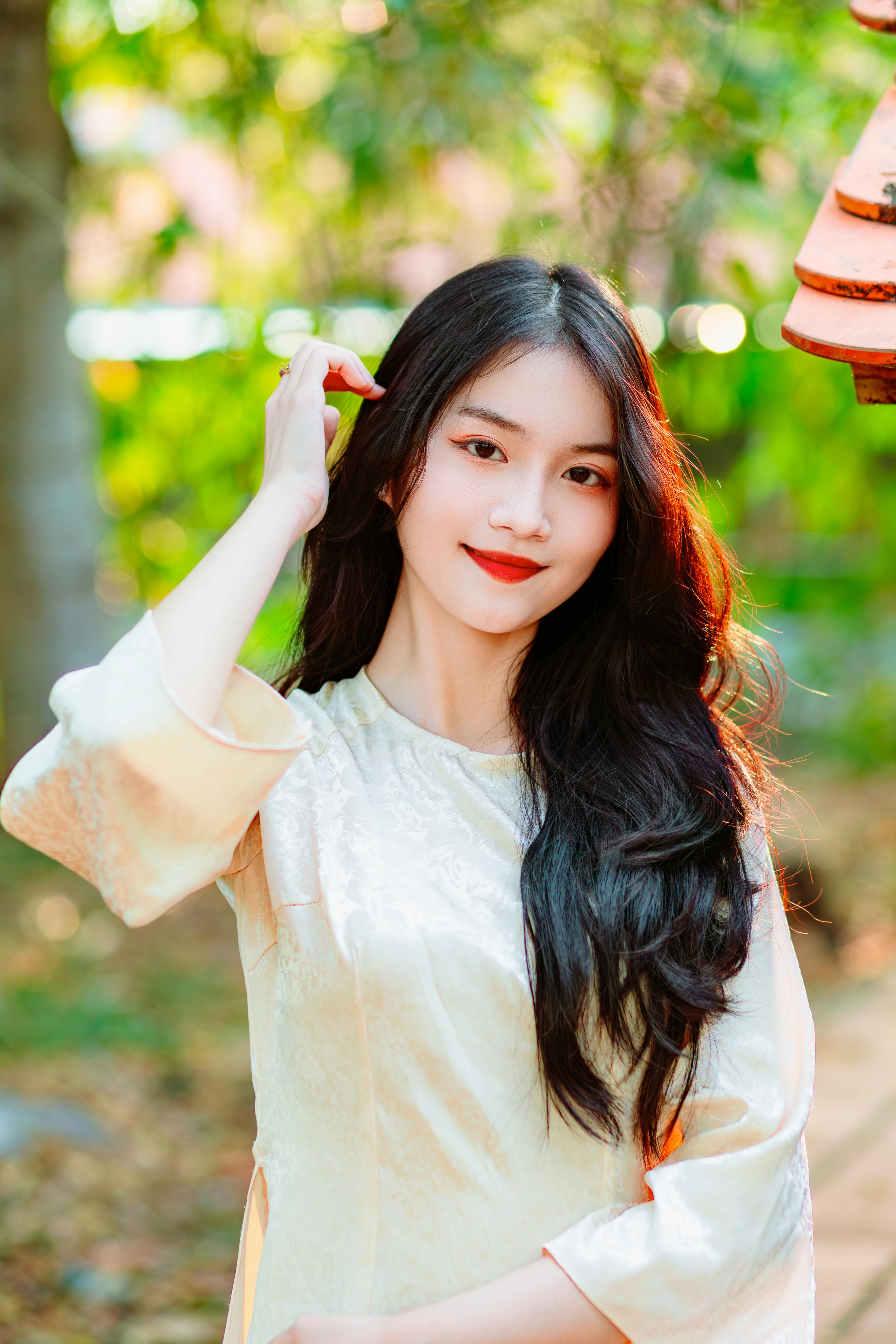 A graceful young woman in a serene outdoor setting, exuding elegance and warmth.