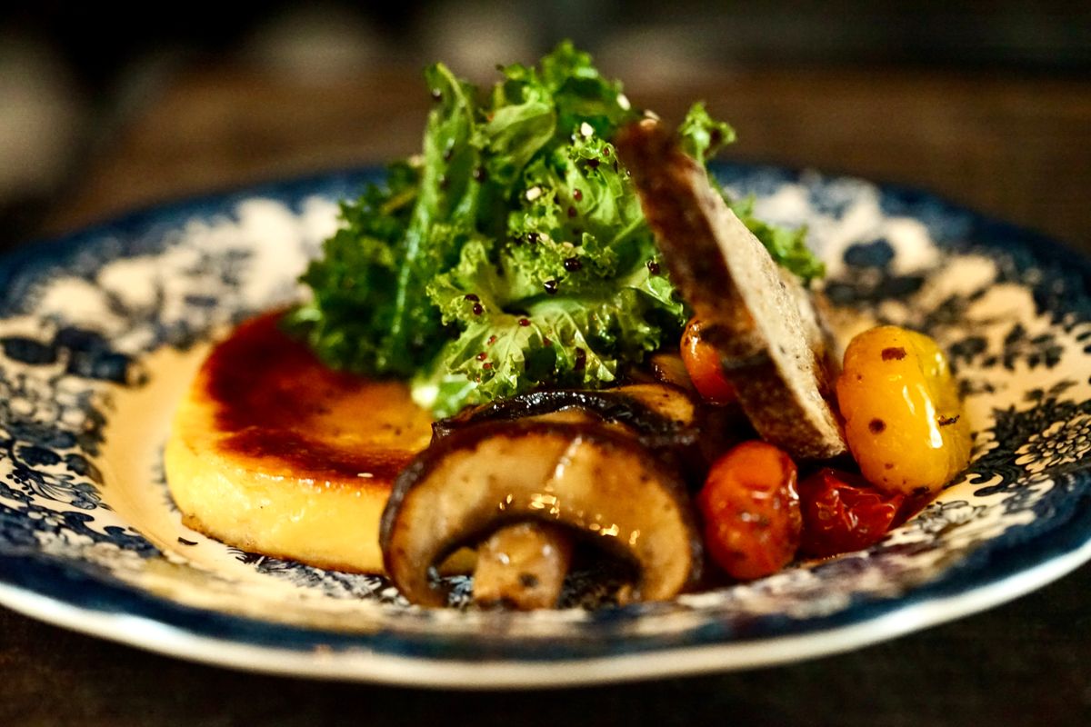 Seared polenta cake with roasted mushrooms, sausage slices, cherry tomatoes and frisee