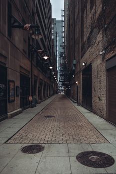 City alleyway with tall buildings creating a dramatic diminishing perspective and an industrial feel.